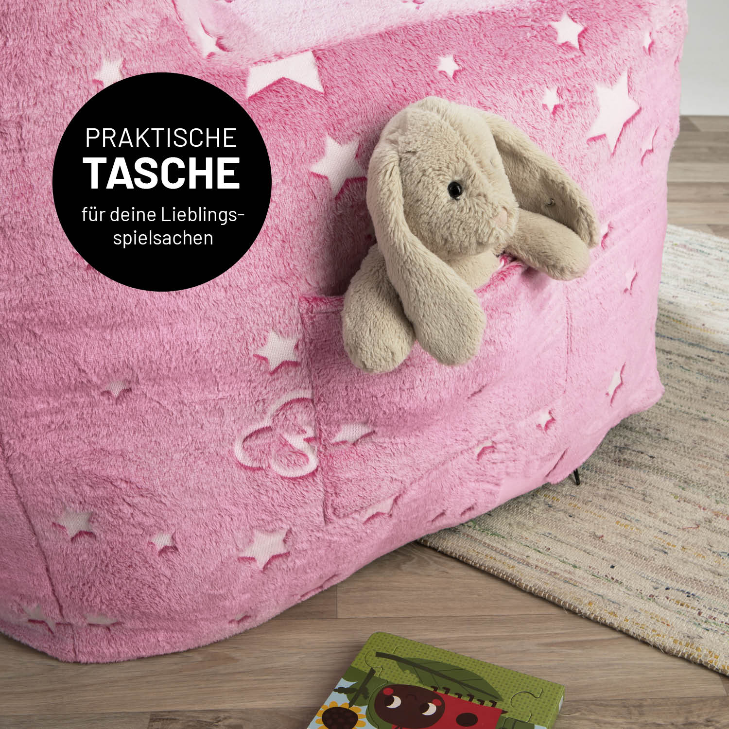 Ein Kuscheltier-Häschen in der praktischen Tasche des pinken LUMALAND Kinder-Sessels "Glow in the Dark".