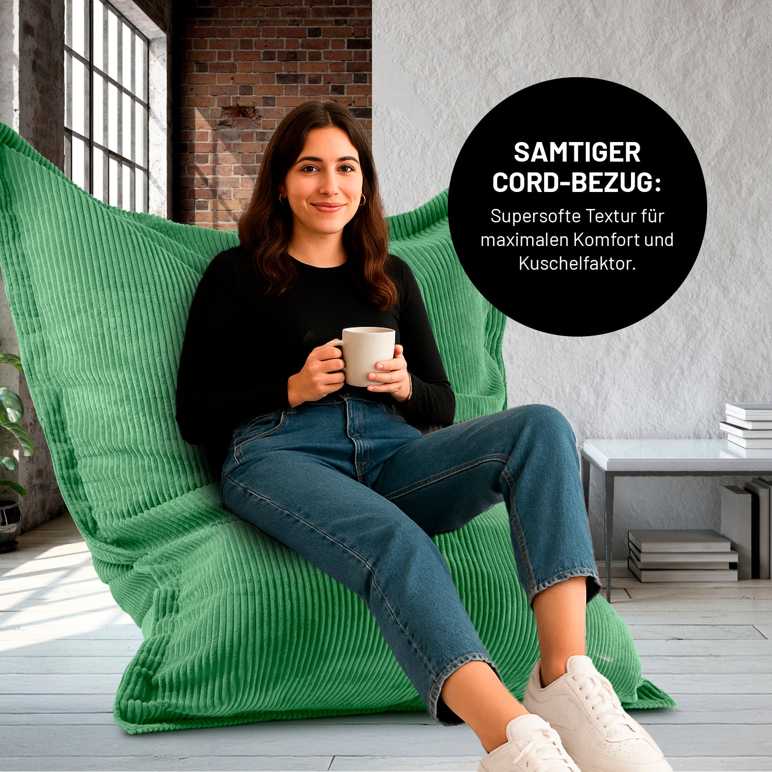 Eine Frau mit Kaffeetasse sitzt in einem Wohnzimmer auf dem XXL-Sitzsack mit Cord Bezug, Icon "Samtiger Cord-Bezug für maximalen Komfort und Kuschelfaktor".