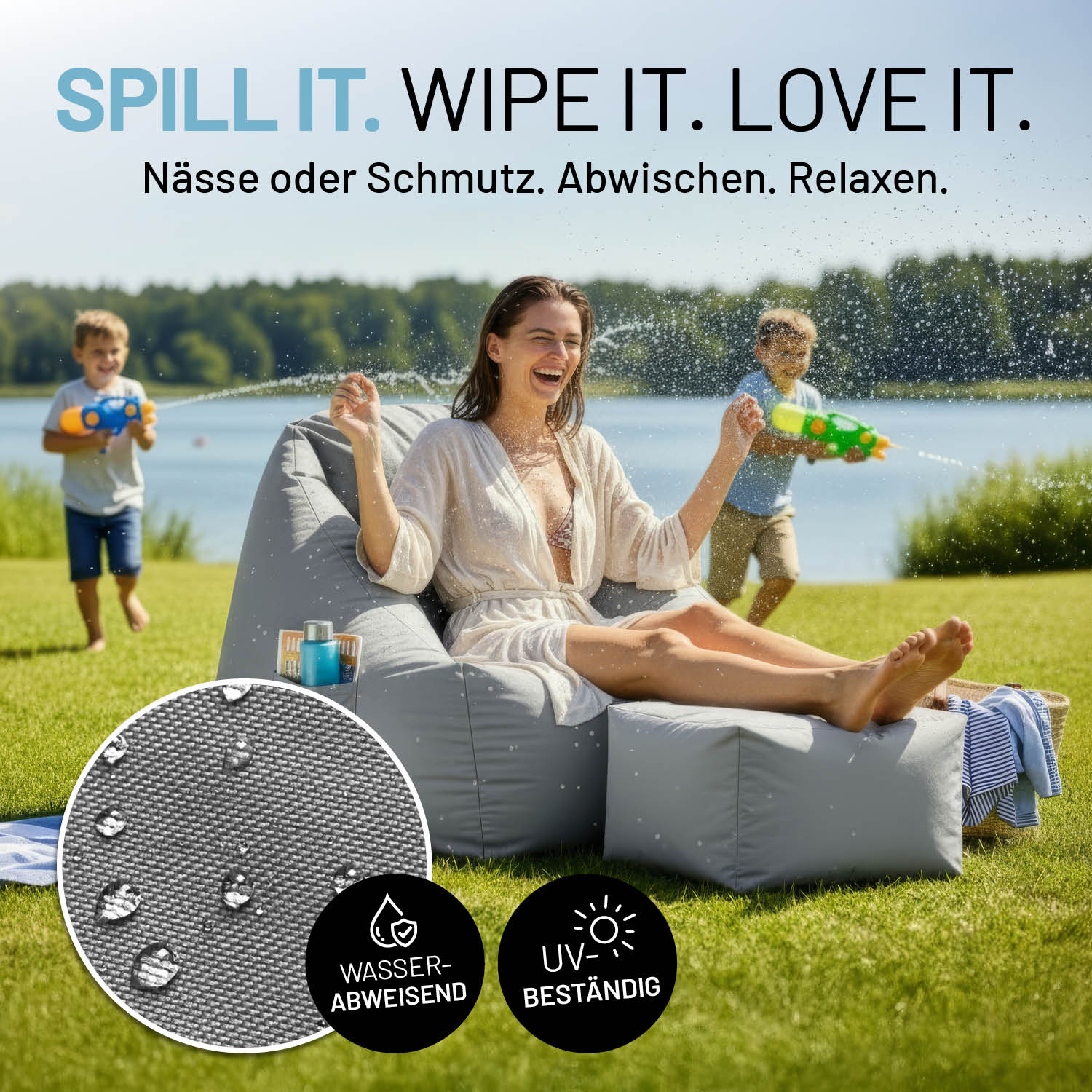 Frau sitzt lachend auf grauem CROZY AIR Sessel und die Füße auf dem Hocker abgelegt am See, Kinder spritzen Wasser. Infos zu "Bezug wasserabweisend", "UV-beständig" und "leicht abwischbar".