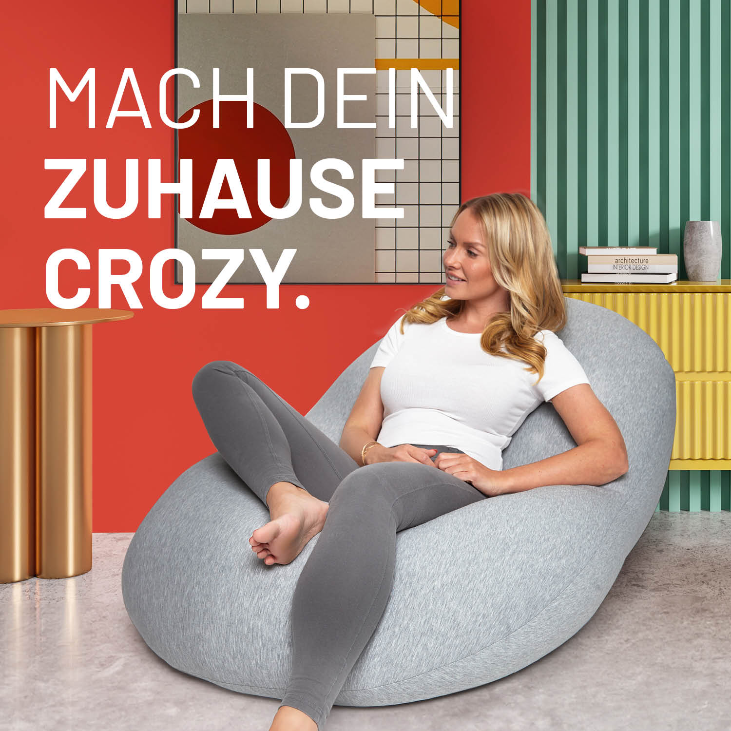 Eine Frau sitzt im flexiblen hellgrauen Sitzsack in einem modernen bunten Wohnzimmer - Mache dein Zuhause Crozy.