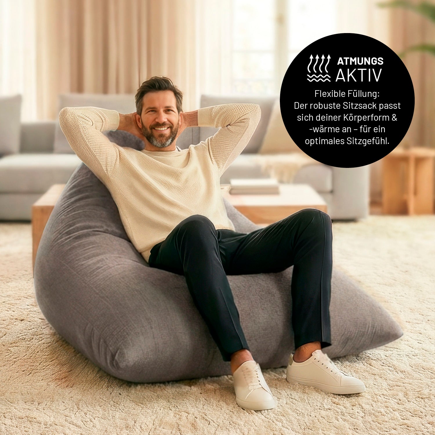 Ein Mann lehnt entspannt auf dem Sitzsack in Hellgrauen in einem Wohnzimmer. Icon zu „atmungsaktiv“ und "flexible Füllung, die sich der Körperform und Wärme anpasst".