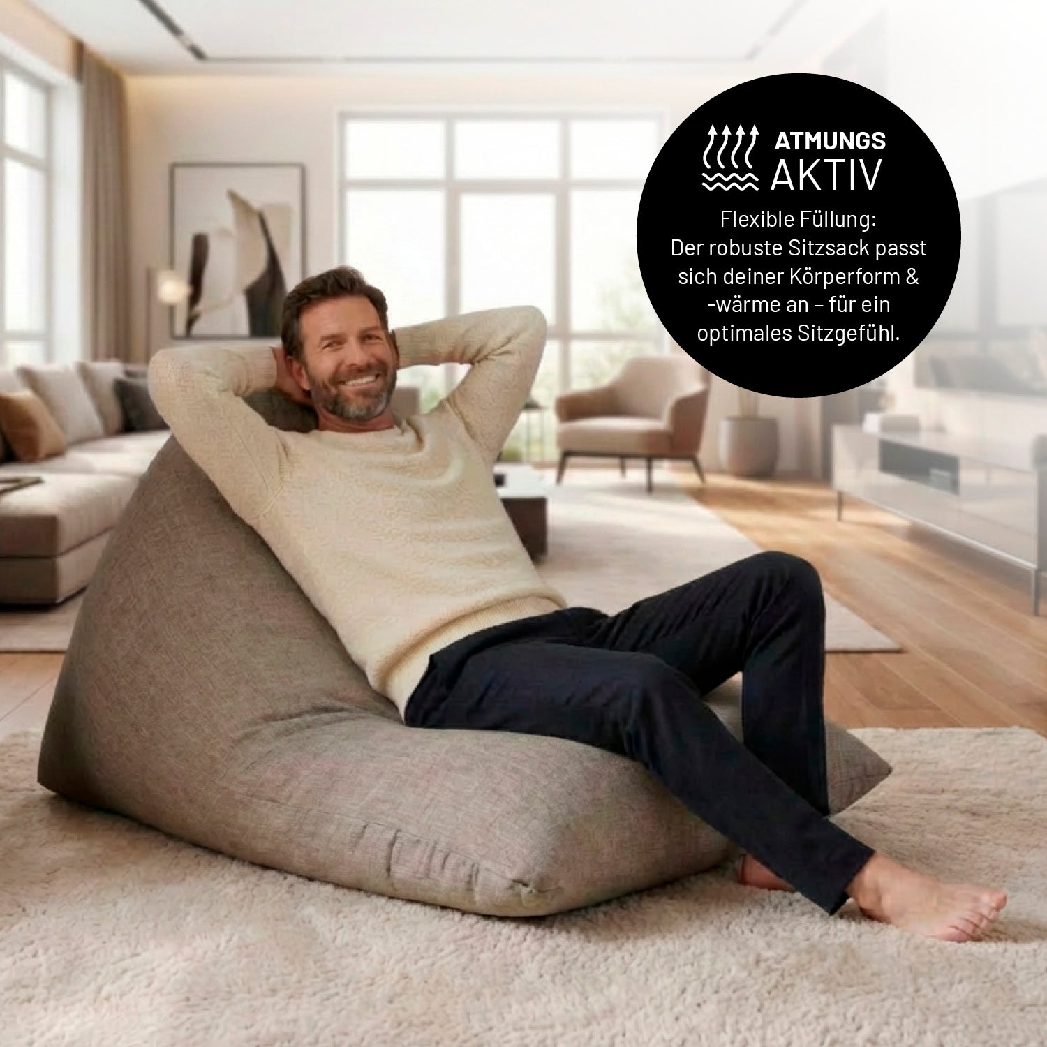 Ein Mann lehnt entspannt auf dem Sitzsack in Hellgrauen in einem Wohnzimmer. Icon zu „atmungsaktiv“ und "flexible Füllung, die sich der Körperform und Wärme anpasst".