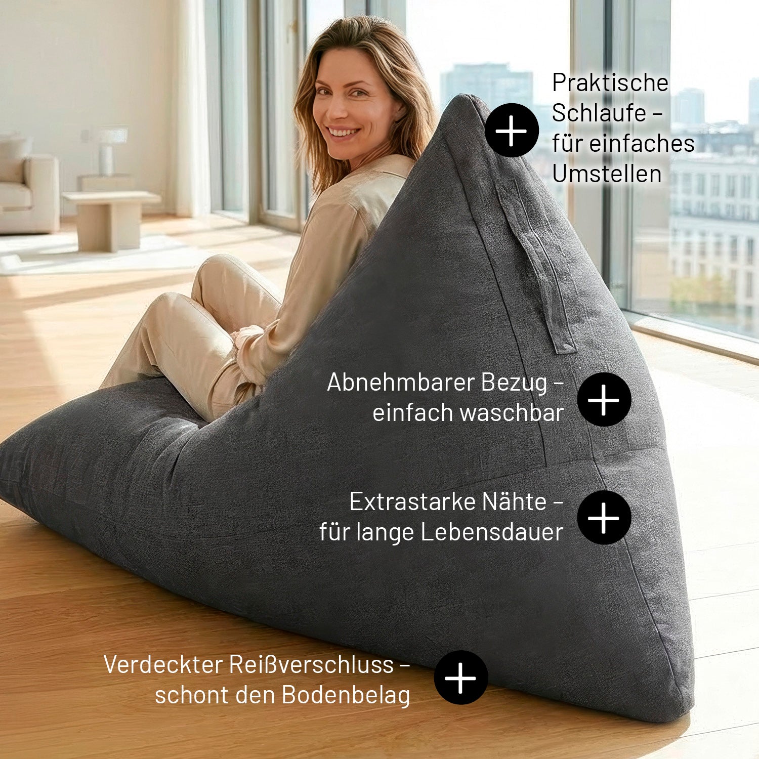 Eine Frau sitzt auf dem dunkelgrauen Sitzsack in Dreiecksform. Infos zu "Mit Schlaufe", "Extrastarke Nähte", "Verdeckter Reißverschluss" und "Abnehmbarer & Waschbarer Bezug".
