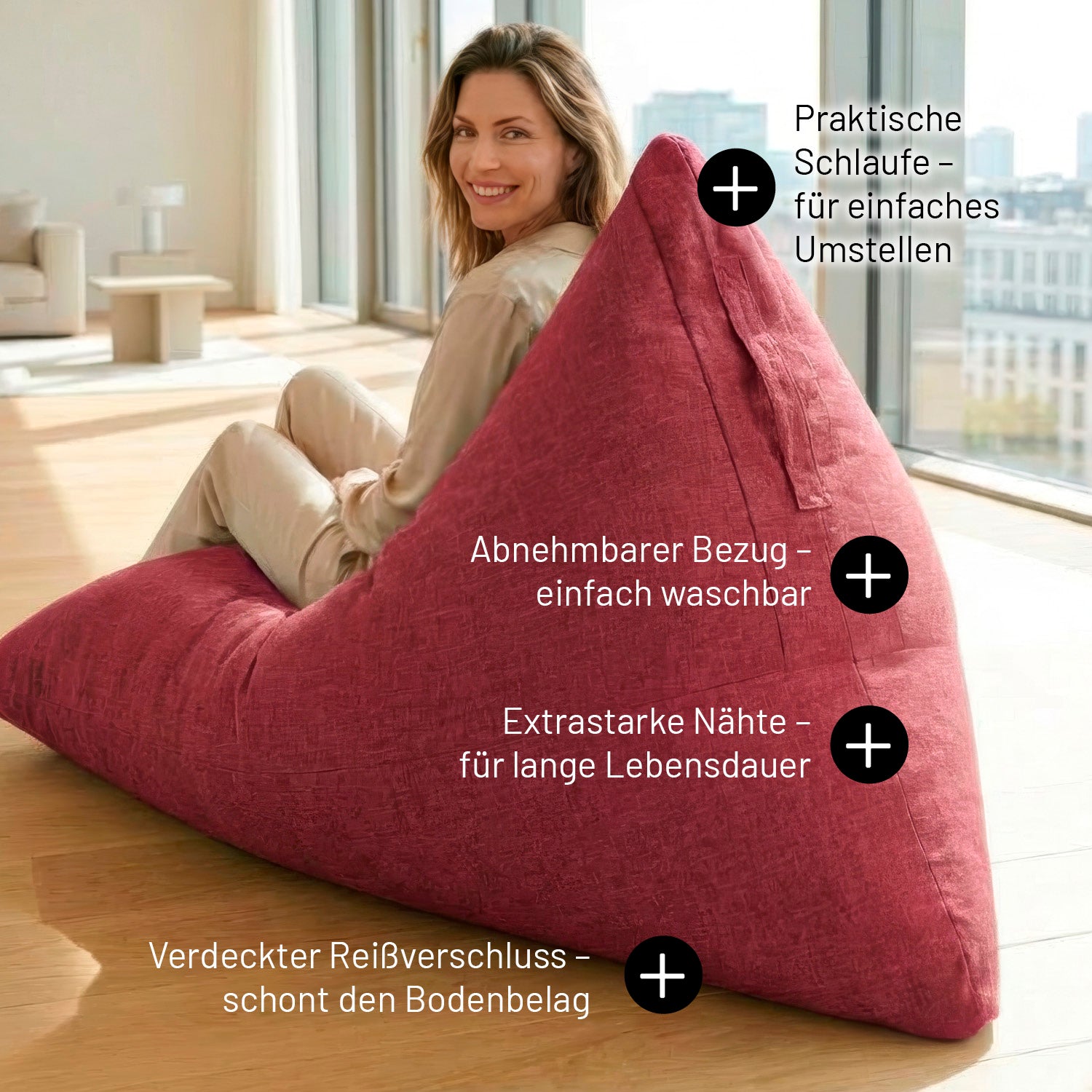 Eine Frau sitzt auf dem roten Sitzsack in Dreiecksform. Infos zu "Mit Schlaufe", "Extrastarke Nähte", "Verdeckter Reißverschluss" und "Abnehmbarer & Waschbarer Bezug".