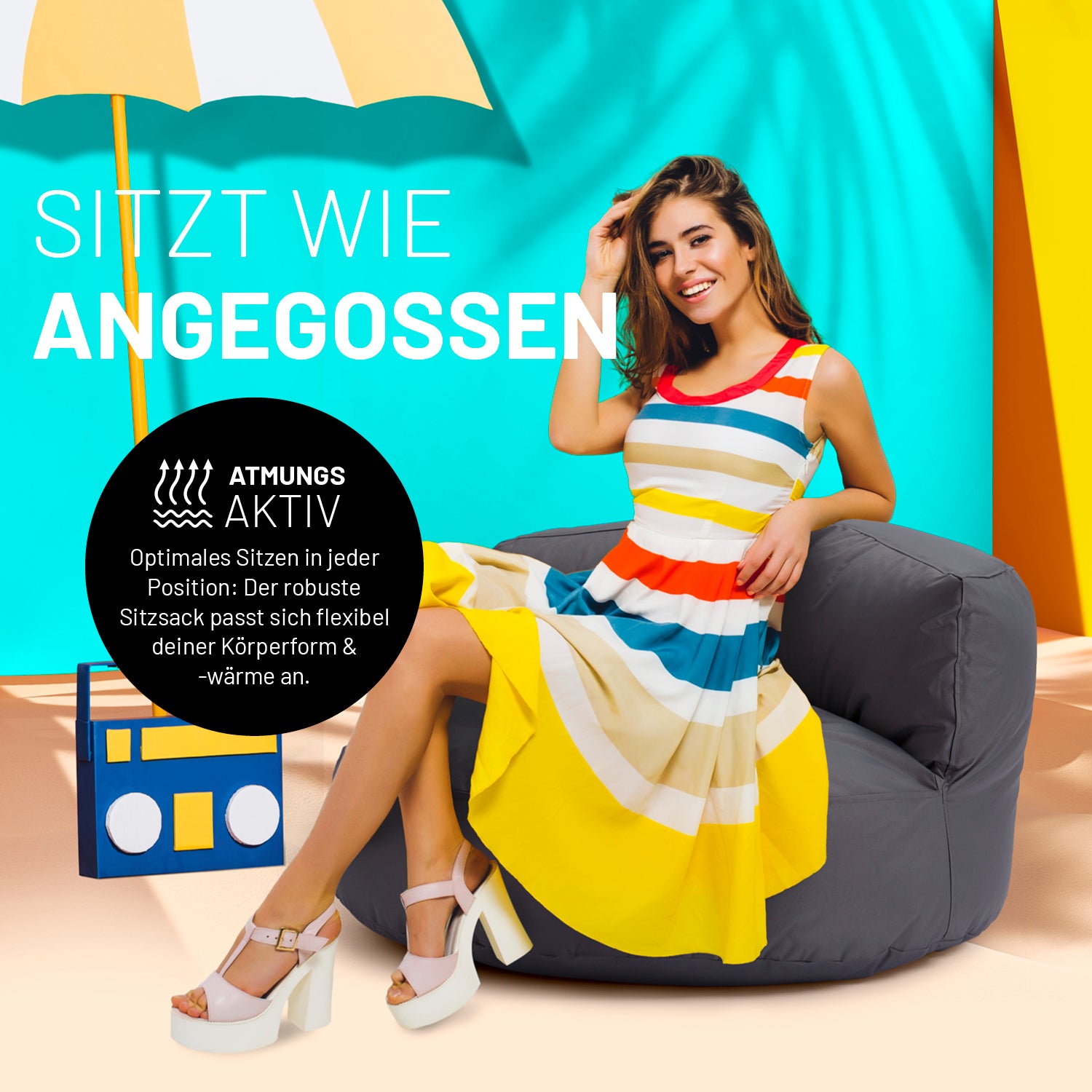 Eine Frau in buntem Kleid sitzt auf dem Sitzsack-Sofa in Anthrazit. Icon "Atmungsaktiv" und "Passt sich Körperform und -wärme an".