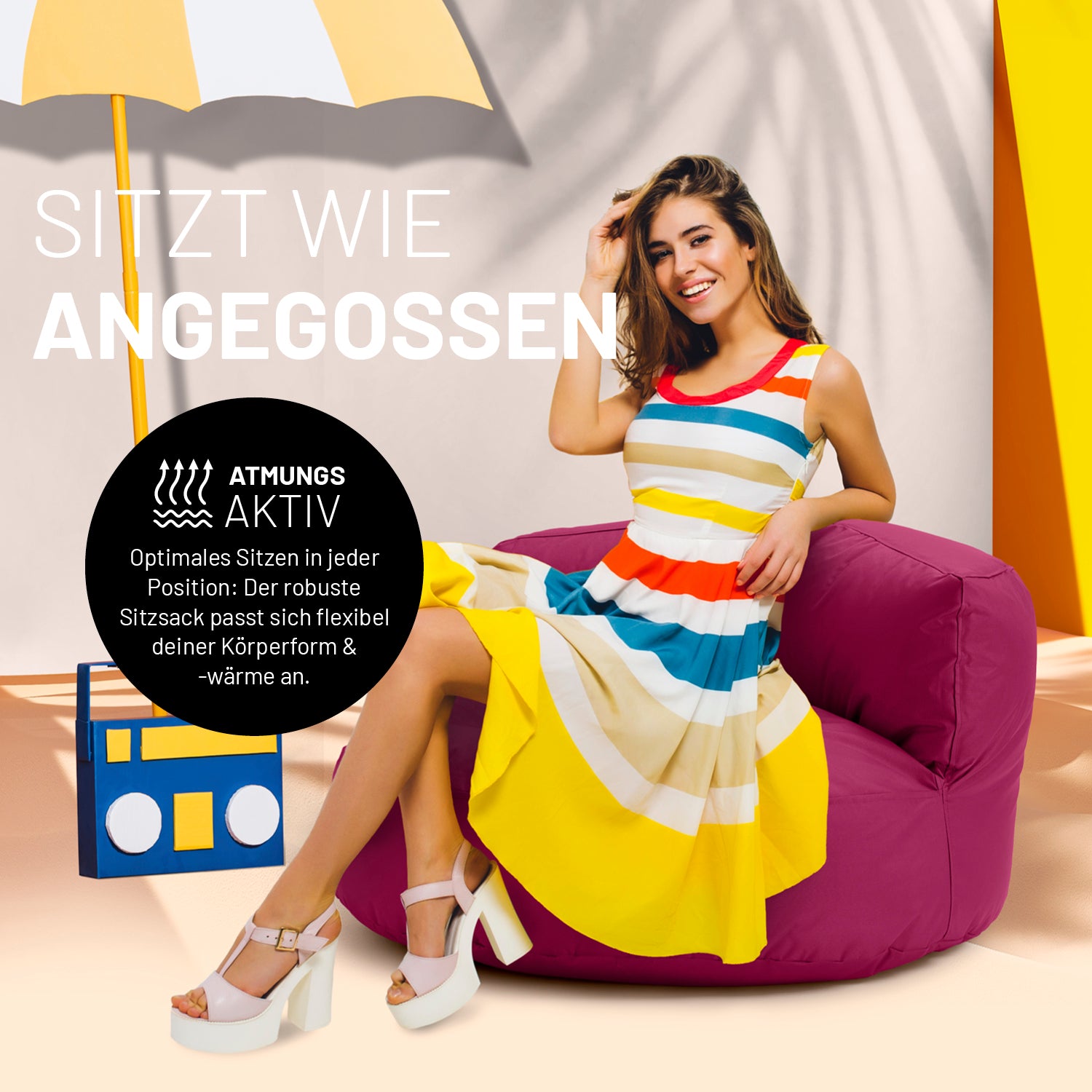 Eine Frau in buntem Kleid sitzt auf dem weinroten Sitzsack-Sofa. Icon "Atmungsaktiv" und "Passt sich Körperform und -wärme an".