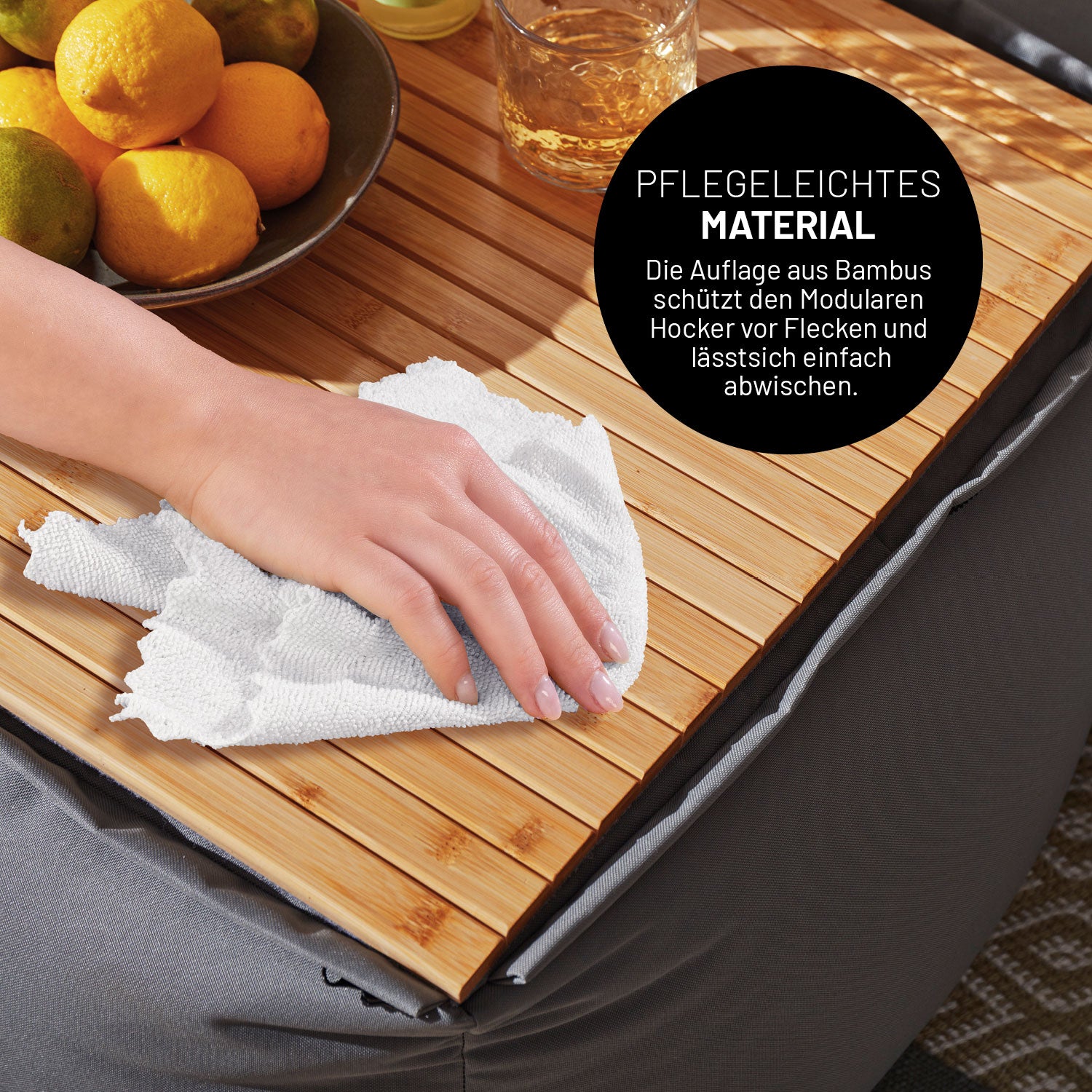 Eine Frau wischt die Bambusablage die auf dem modularen Hocker liegt mit einem Tuch ab.