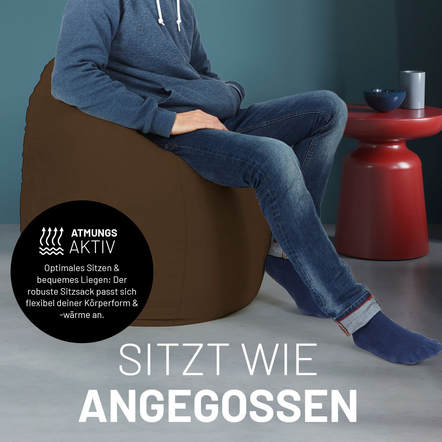 Ein Mann sitzt im braunen Sitzsack, dahinter ein roter Tisch. Icon "Atmungsaktiv - Passt sich der Körperform und -wärme an".
