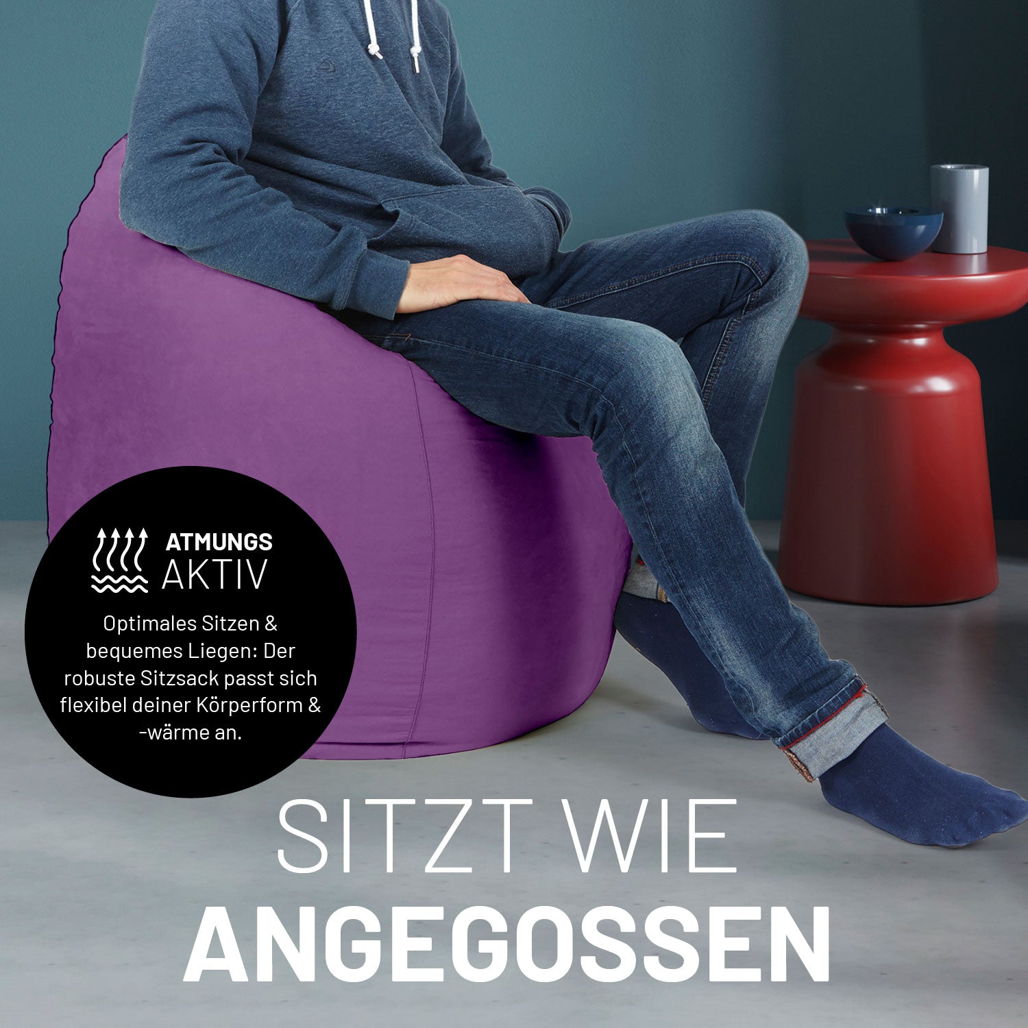 Ein Mann sitzt im lila Sitzsack, dahinter ein roter Tisch. Icon "Atmungsaktiv - Passt sich der Körperform und -wärme an".