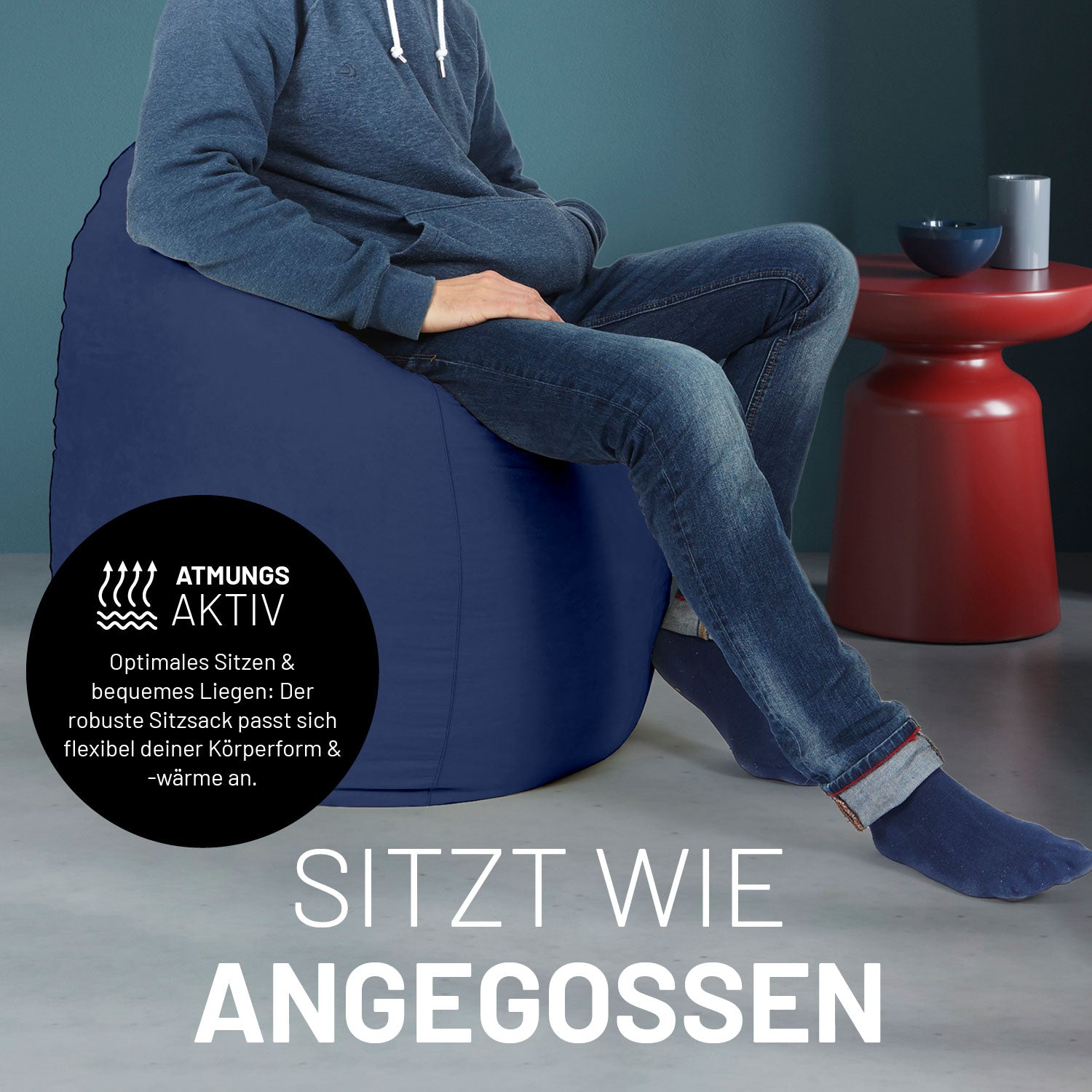 Ein Mann sitzt im navyblauen Sitzsack, dahinter ein roter Tisch. Icon "Atmungsaktiv - Passt sich der Körperform und -wärme an".