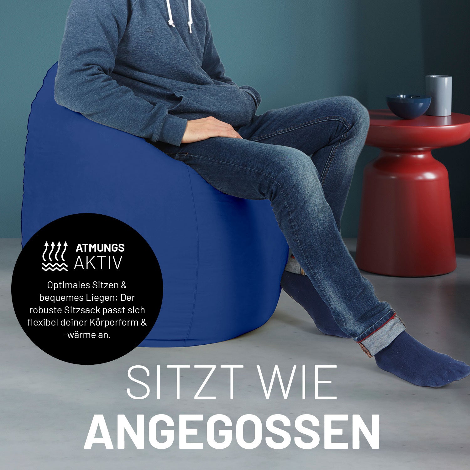 Ein Mann sitzt im royalblauen Sitzsack, dahinter ein roter Tisch. Icon "Atmungsaktiv - Passt sich der Körperform und -wärme an".