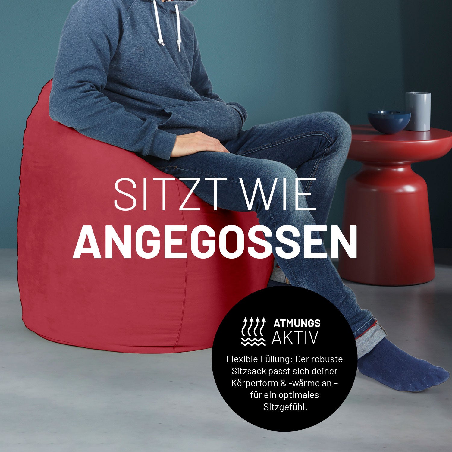 Ein Mann sitzt im roten Sitzsack, dahinter ein roter Tisch. Icon "Atmungsaktiv - Passt sich der Körperform und -wärme an".
