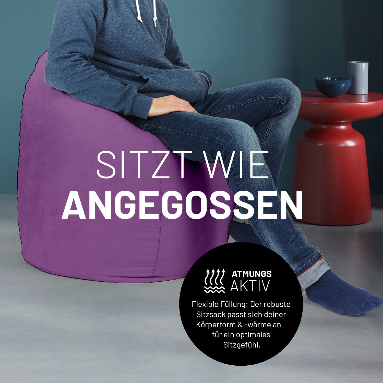 Ein Mann sitzt im lilanen Sitzsack, dahinter ein roter Tisch. Icon "Atmungsaktiv - Passt sich der Körperform und -wärme an".