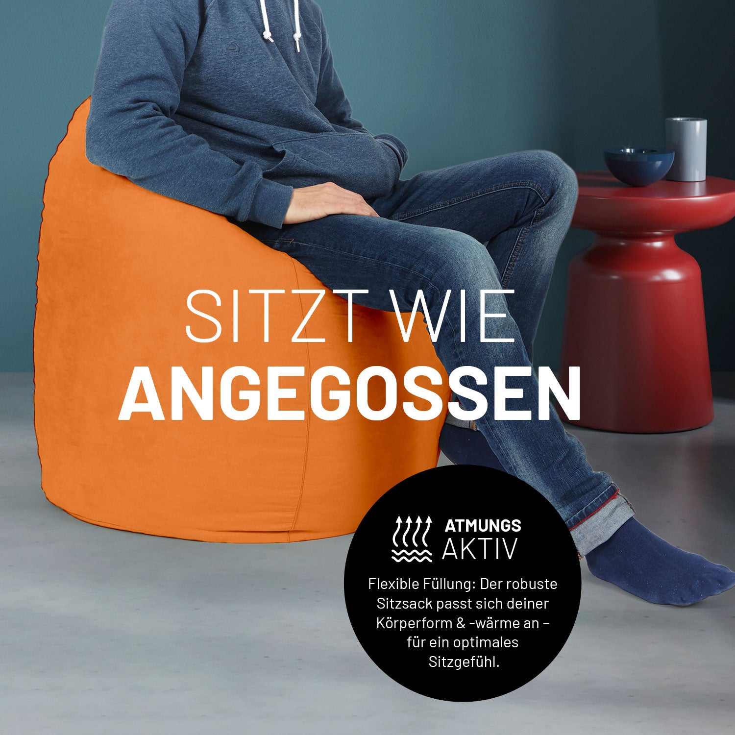 Ein Mann sitzt im orangenen Sitzsack, dahinter ein roter Tisch. Icon "Atmungsaktiv - Passt sich der Körperform und -wärme an".