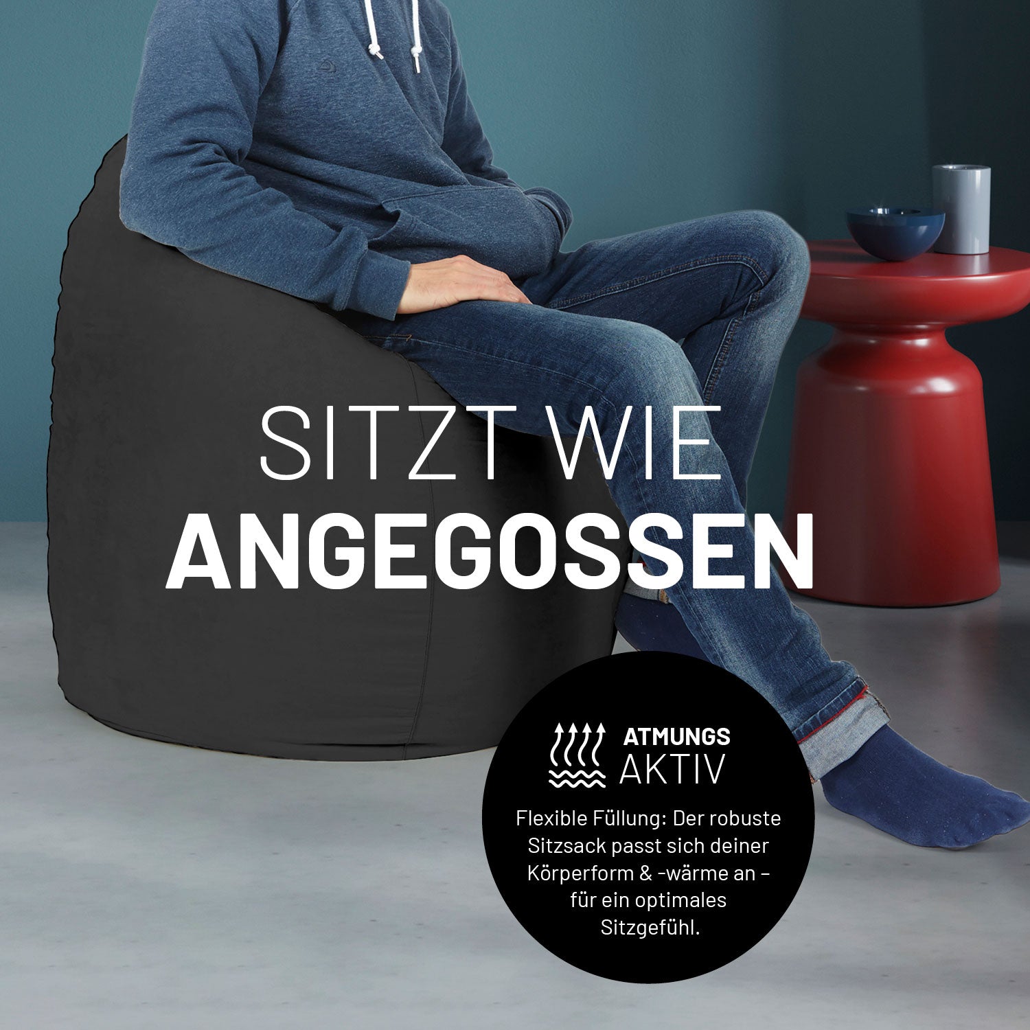 Ein Mann sitzt im schwarzen Sitzsack, dahinter ein roter Tisch. Icon "Atmungsaktiv - Passt sich der Körperform und -wärme an".