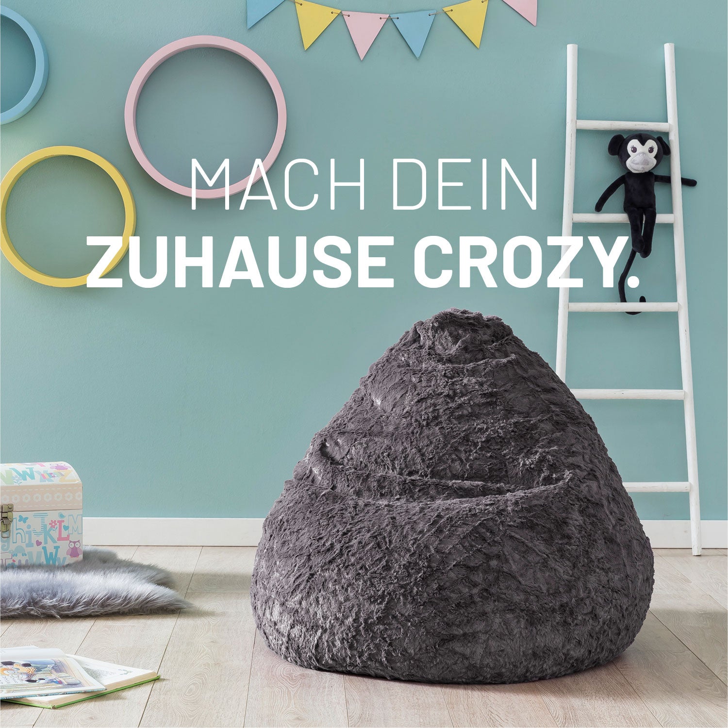 Grauer Fluffy Sitzsack für Kinder in einem Kinderzimmer, im Hintergrund ein Affen-Kuscheltier auf einer Leiter.