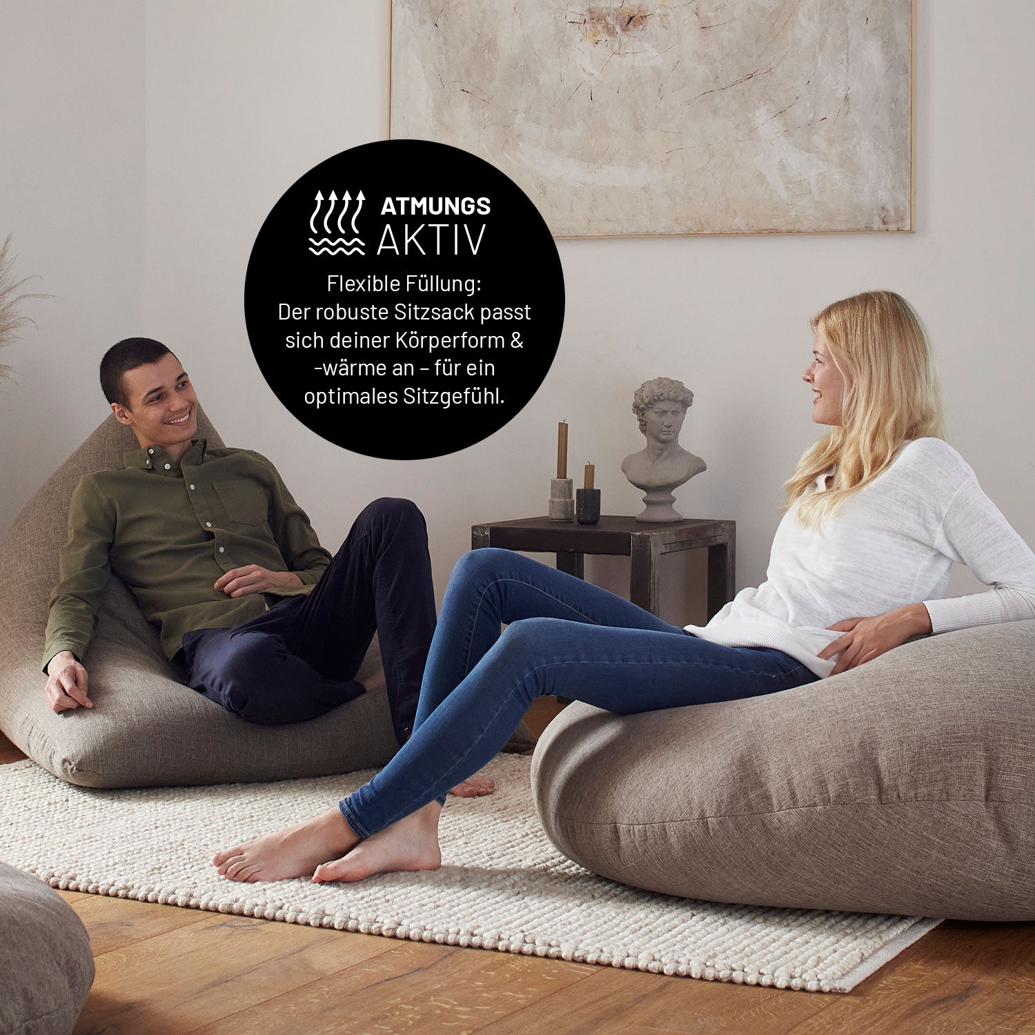 Ein Mann und eine Frau entspannen auf den 2 in 1 Sitzsäcken in einem modernen Wohnzimmer. Die Szene betont den atmungsaktiven, anpassungsfähigen Komfort.