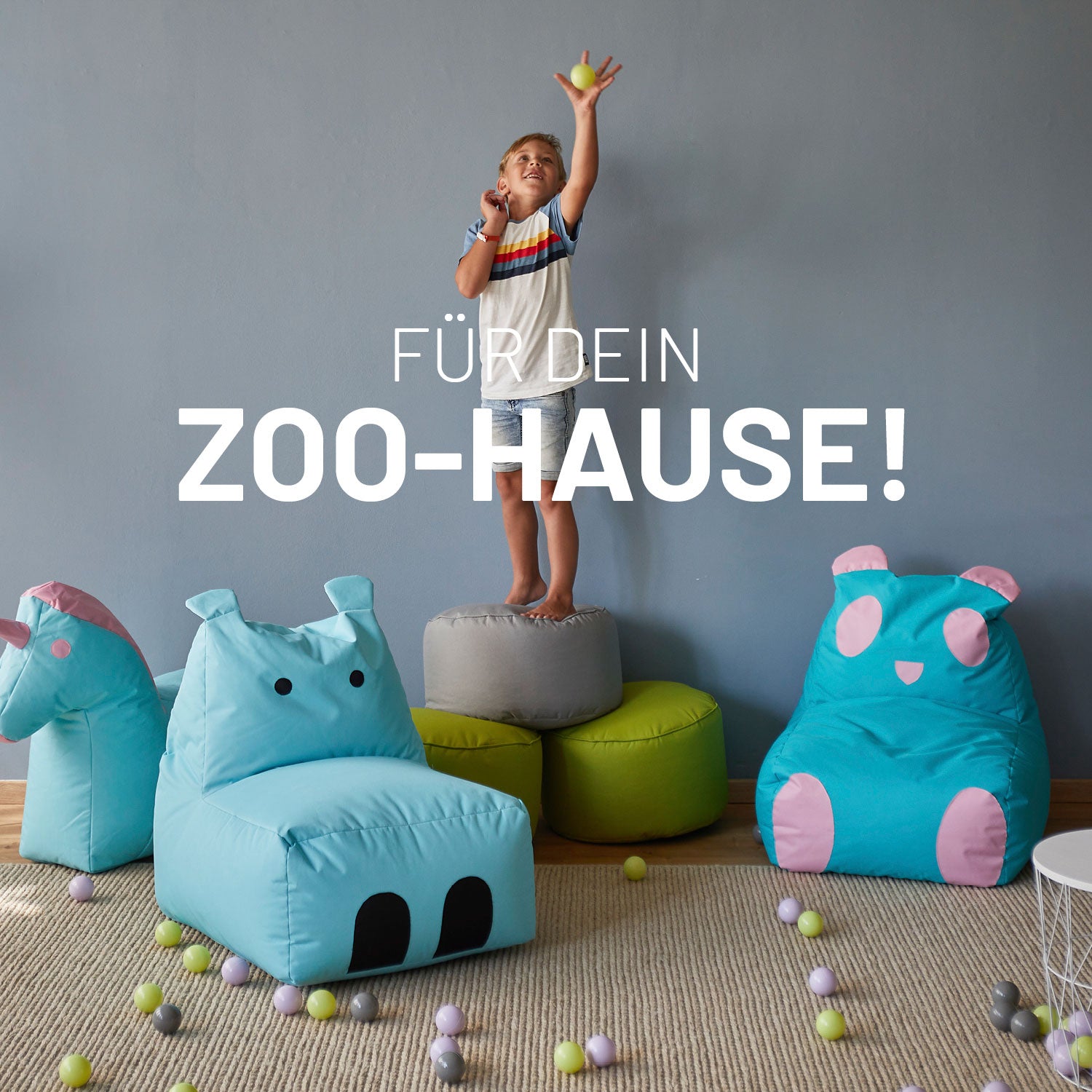 Ein kleiner Junge spielt auf passenden Poufs zu den Kindersitzsäcken, neben ihm das Einhorn, Hippo und der Panda.
