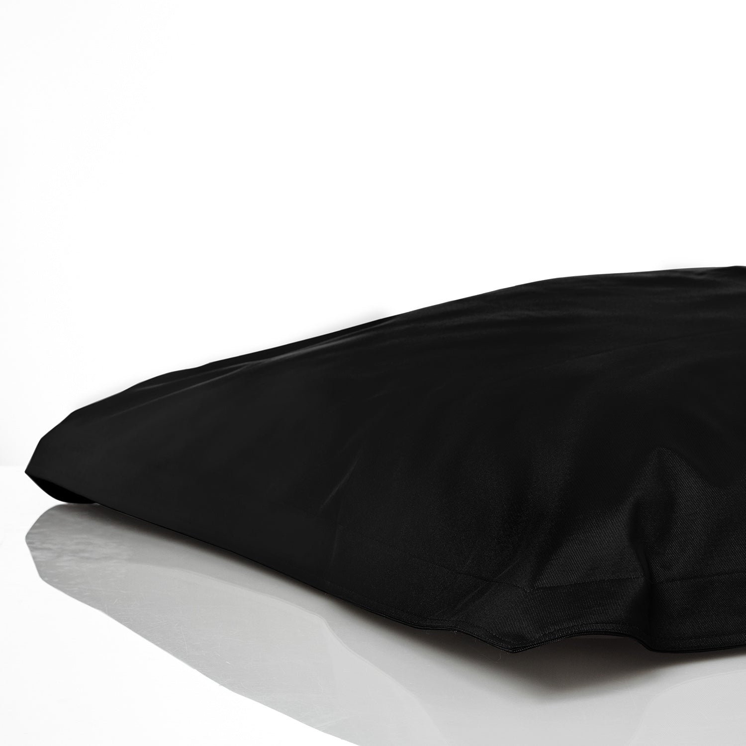 Sitzsackhülle in Schwarz auf dem Boden liegend vor weißen Hintergrund.