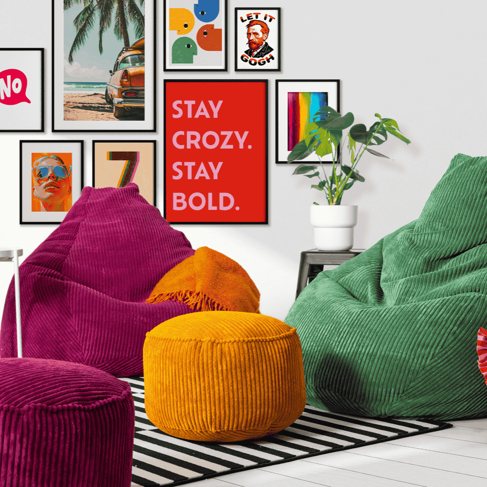Bunte Wohnszene mit Cord-Sitzsäcken in Weinrot und Dunkelgrün sowie senfgelbem Pouf, schwarzem Streifenteppich, Wandbildern und Pflanze.