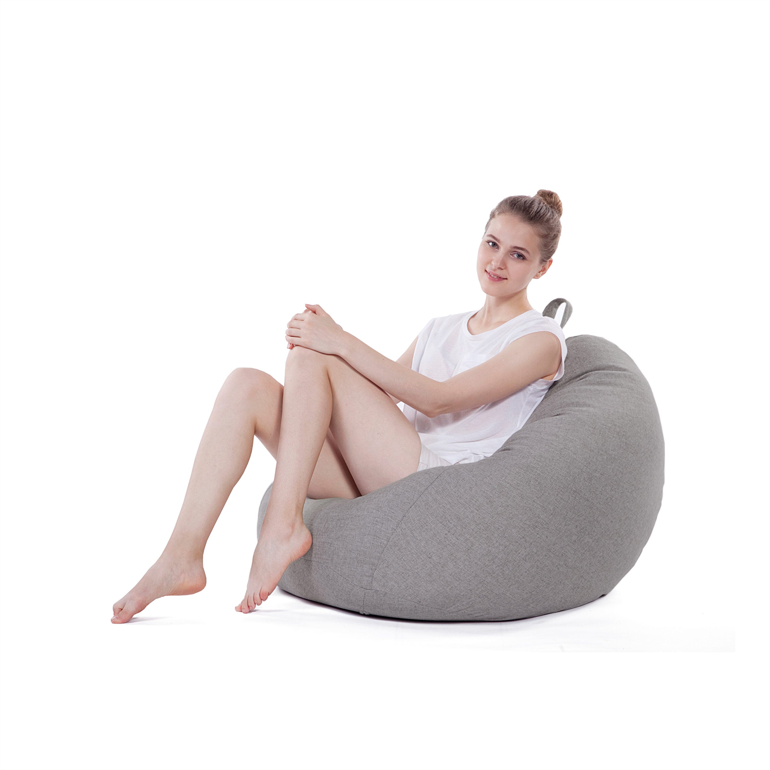 Eine Frau sitzt gemütlich im Comfort Line Sitzsack in Hellgrau und schaut zu in die Kamera.