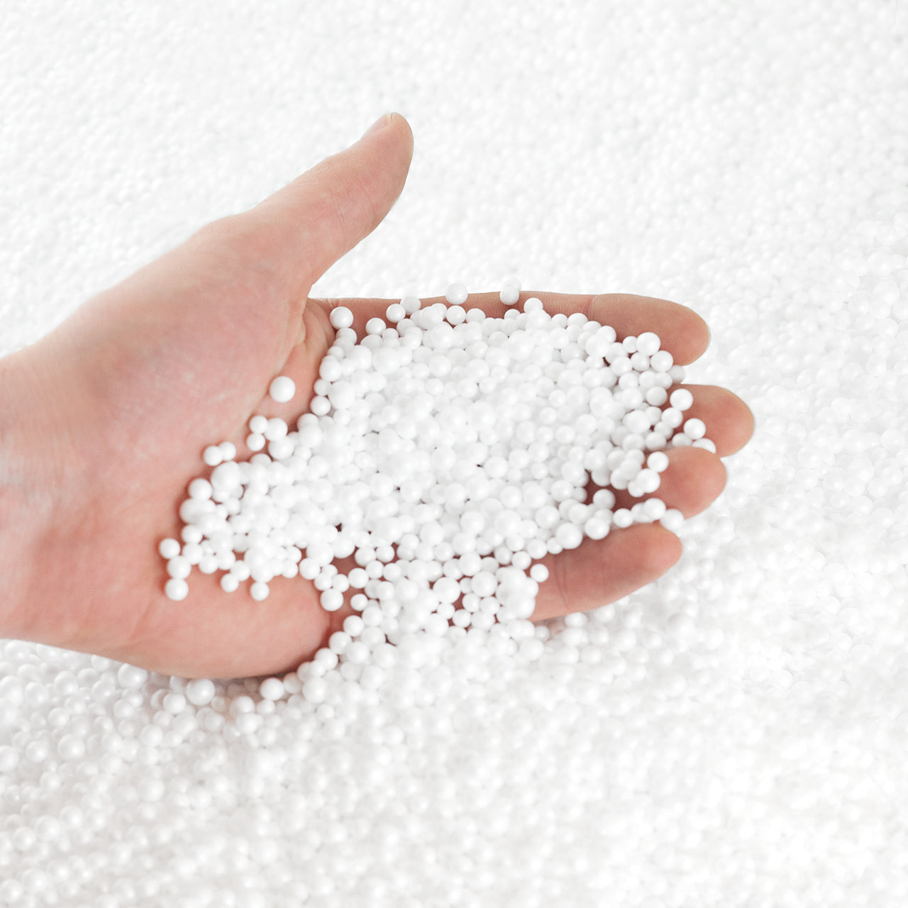 Eine Hand fasst in die EPS-Perlen für die Füllung eines Sitzsackes.