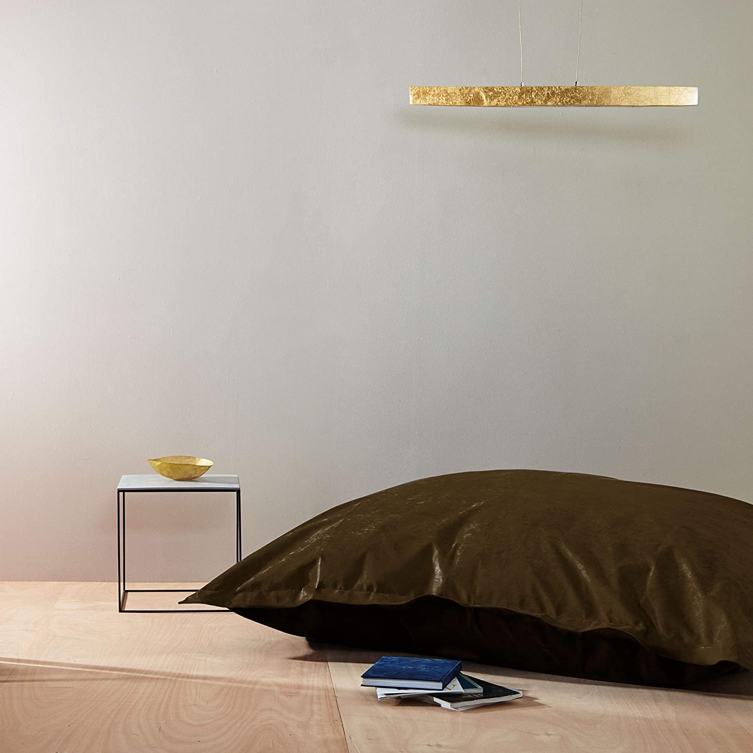Der braune XXL Microvelours Sitzsack liegt in einem spartanisch eingerichteten Raum als Sitzkissen auf dem Boden.