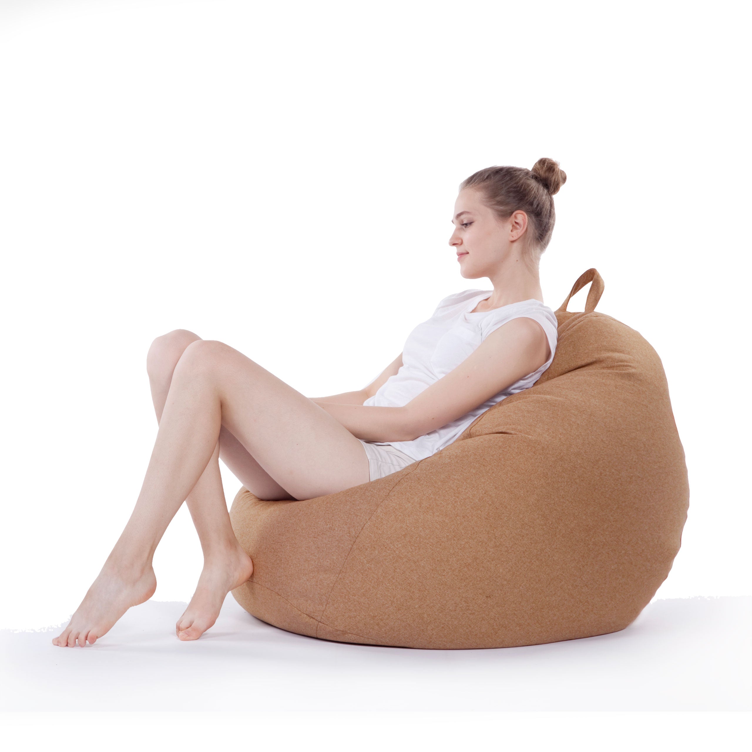 Eine Frau sitzt gemütlich im Comfort Line Sitzsack in Braun und schaut zu Boden.