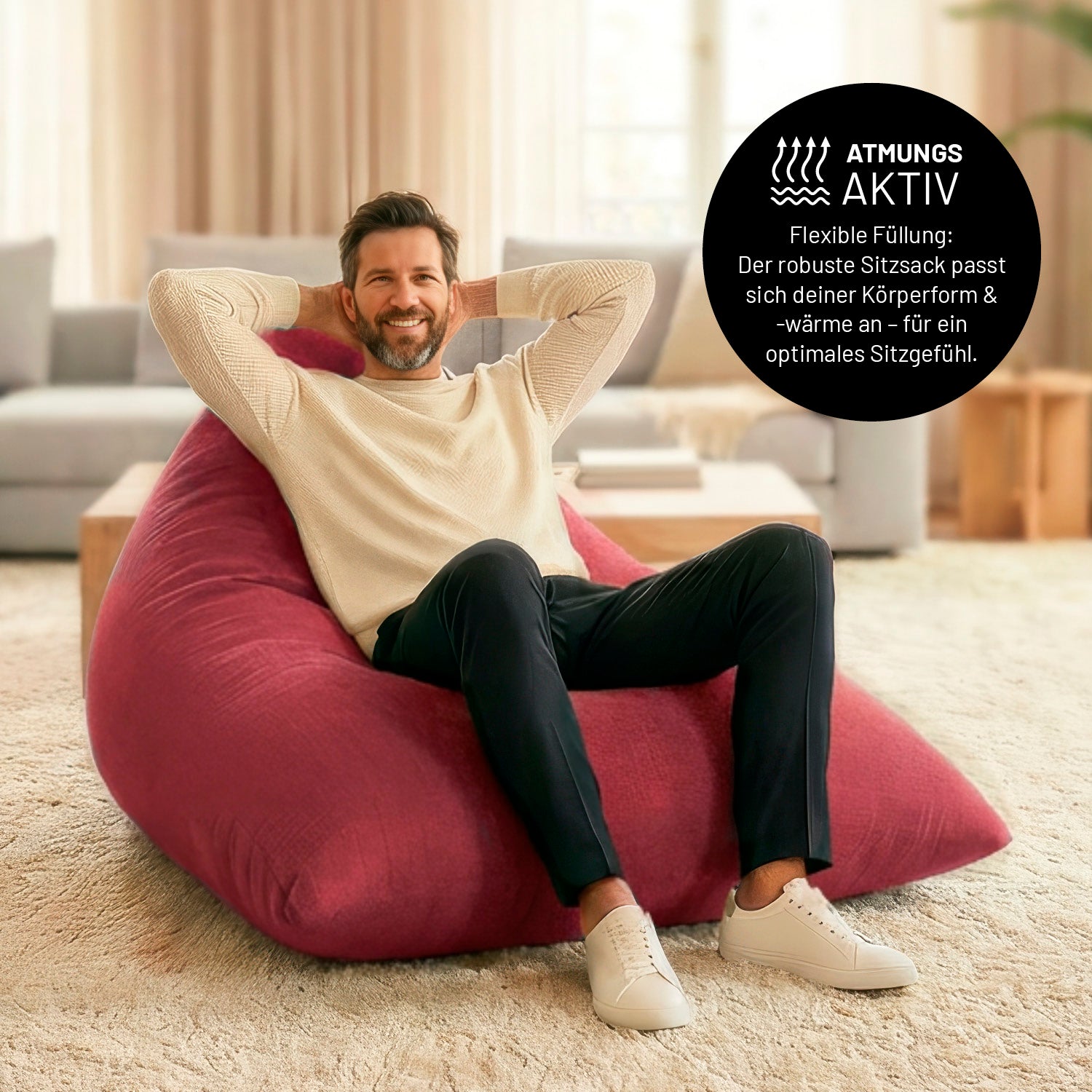 Ein Mann lehnt entspannt auf dem Sitzsack in Rot in einem Wohnzimmer. Icon zu „atmungsaktiv“ und "flexible Füllung, die sich der Körperform und Wärme anpasst".