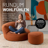 Eine Frau sitzt in einem modernen Wohnzimmer auf dem Sitzsack Lounge-Sofa aus der LUMALAND Teddy-Reihe, Hocker und Beistelltisch daneben.