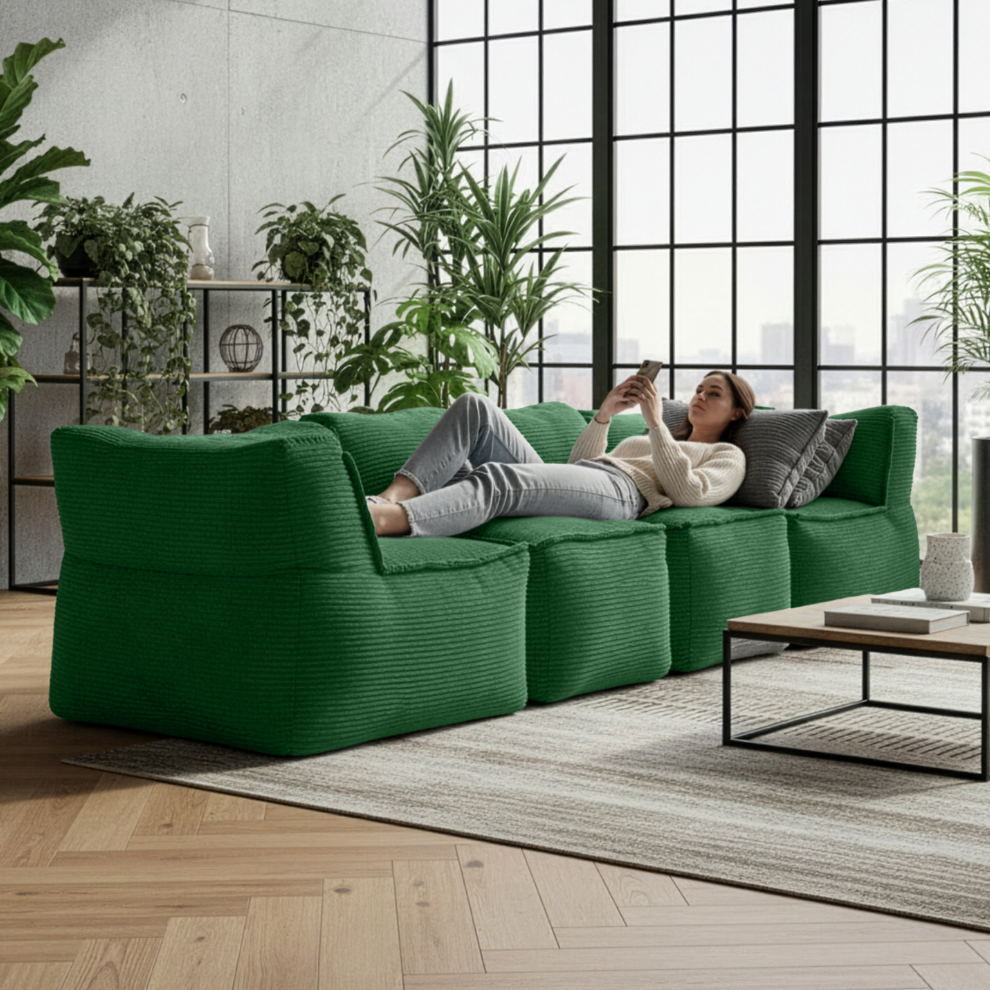 Modulares LUMALAND Sitzsystem in Dunkelgrün: mehrere Cord-Module als Sofa kombiniert, eine Frau entspannt liegend im modernen Wohnraum mit Pflanzen.